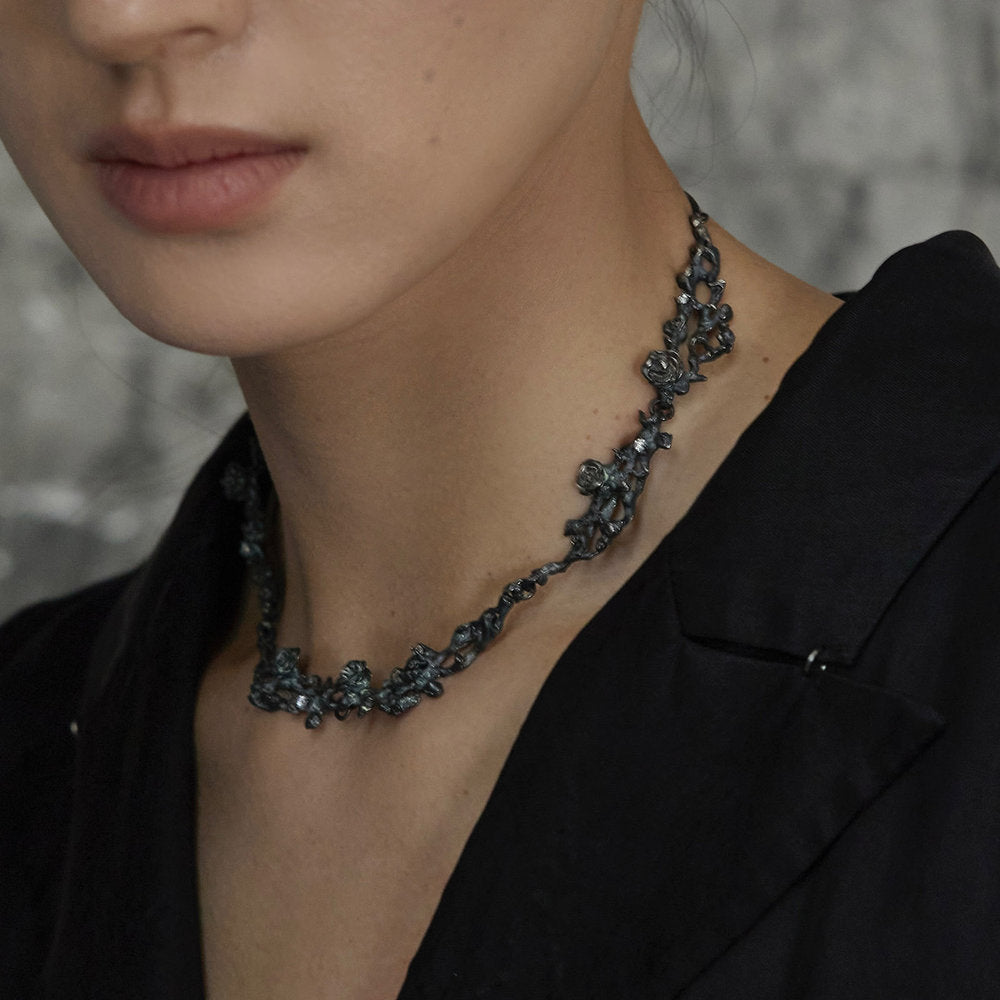Close-up of a person wearing an Oxidized Silver Rose Branch Necklace