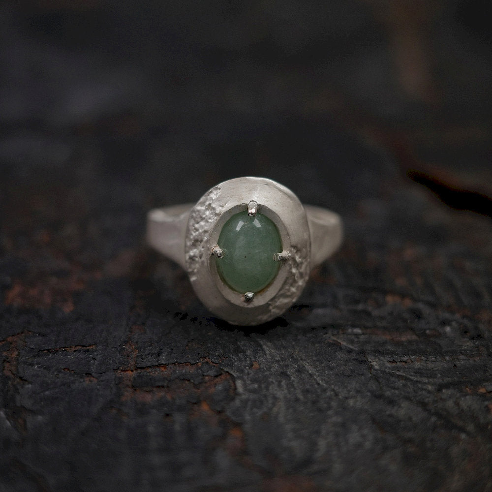Adjustable Silver ring with a green gemstone on a dark textured surface