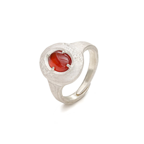 Textured silver ring with a red stone on a white background
