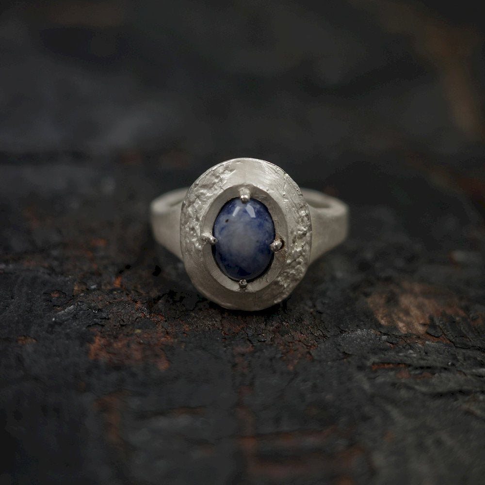 Designer ring with a blue gemstone on a dark textured surface