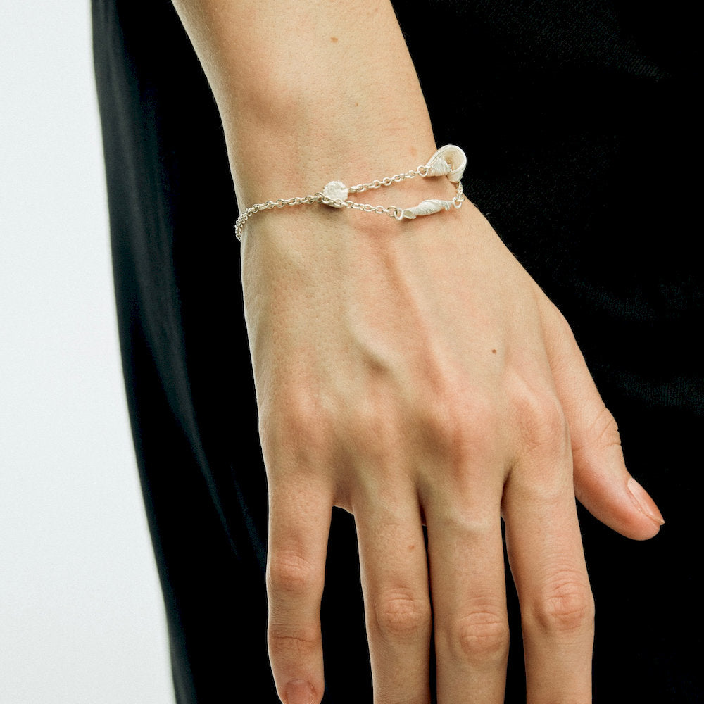 Hand wearing a delicate adjustable silver bracelet with twist details
