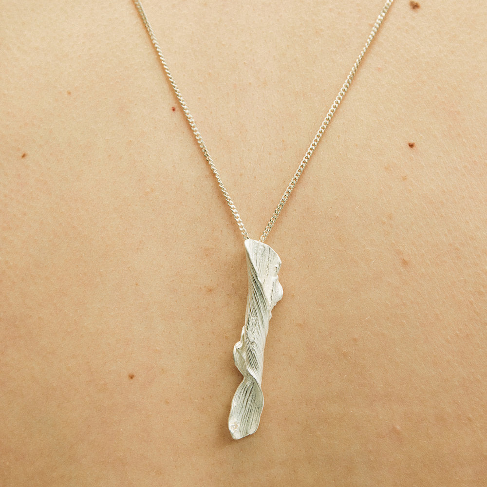 Silver branch-shaped pendant necklace on a person's neck
