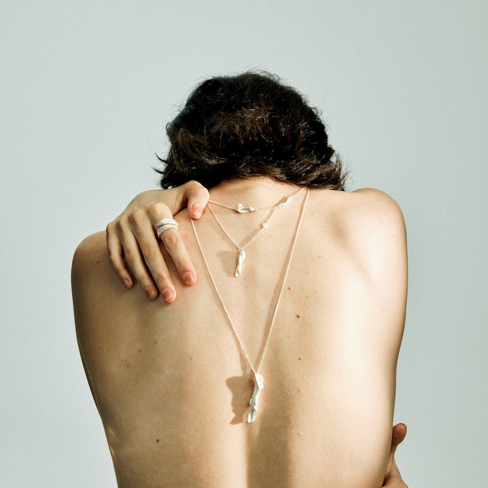 Person wearing a matching set of delicate necklaces and a Linear Double Ring from linework collection