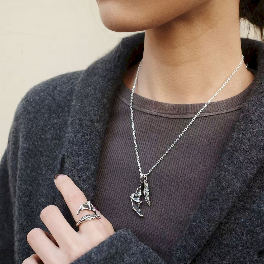 Person wearing a set of Oxidized Silver necklace with a dragon wing pendant and a matching ring.