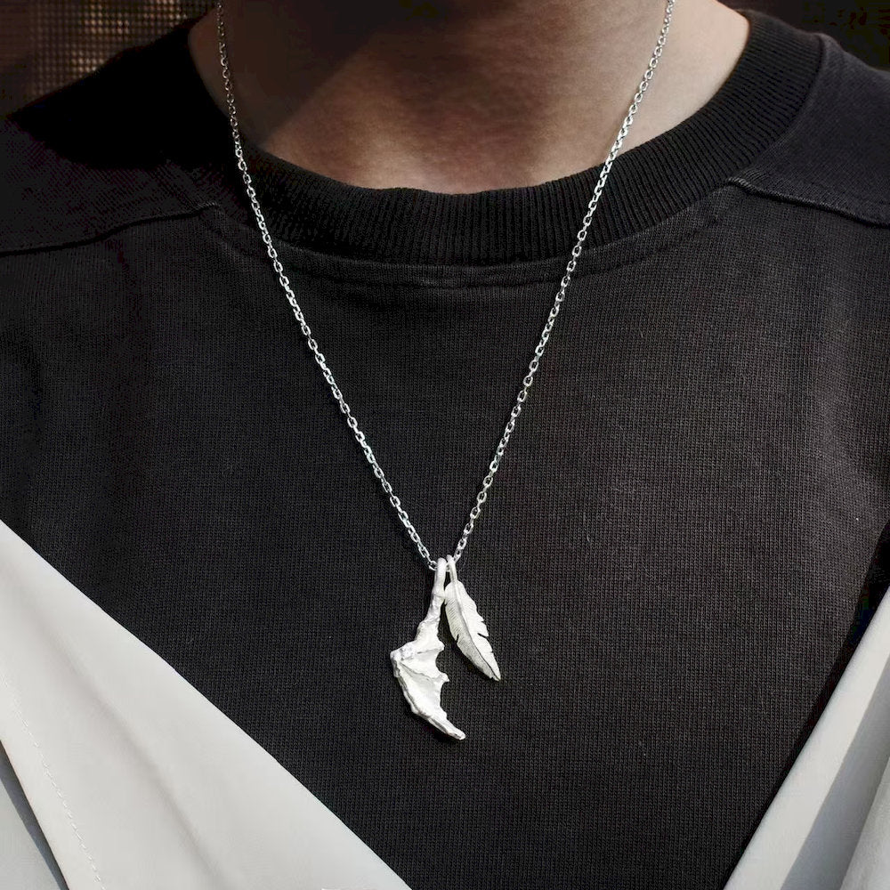 Silver necklace with a unique pendant on a black shirt