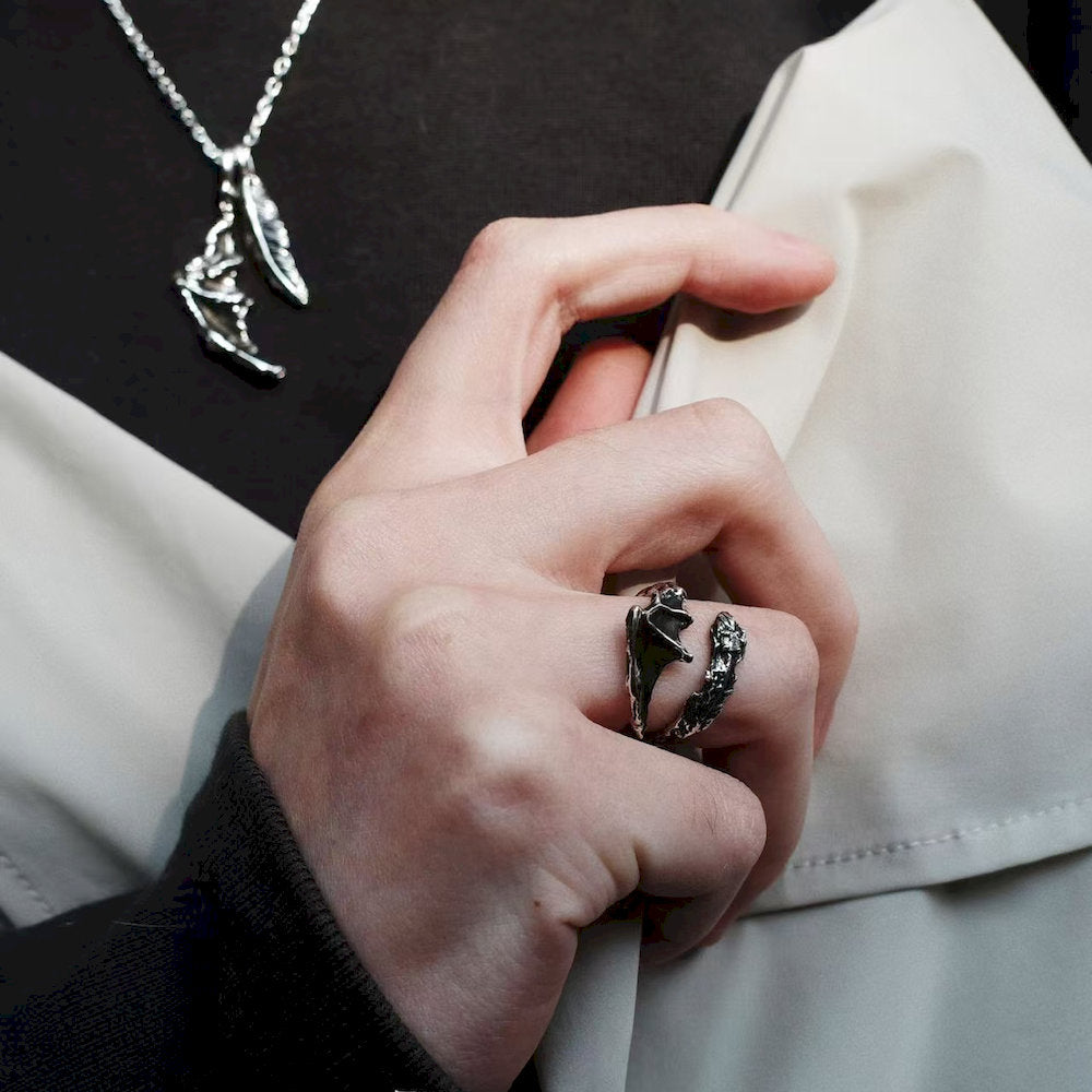 Hand wearing a black silver ring with a detailed design