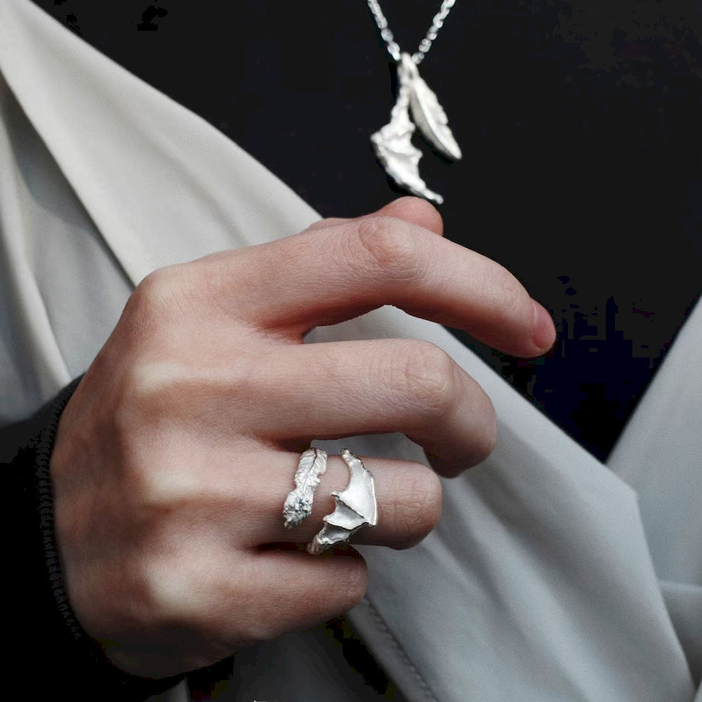 Hand wearing a handmade silver ring with a matching necklace