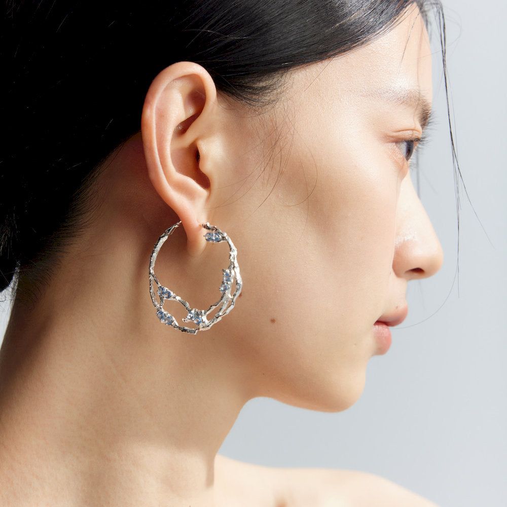 Close-up of a woman wearing a silver hoop earring with Blue Spinel stones