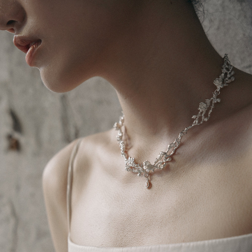 Close-up of a woman wearing an elegant nature-inspired silver necklace