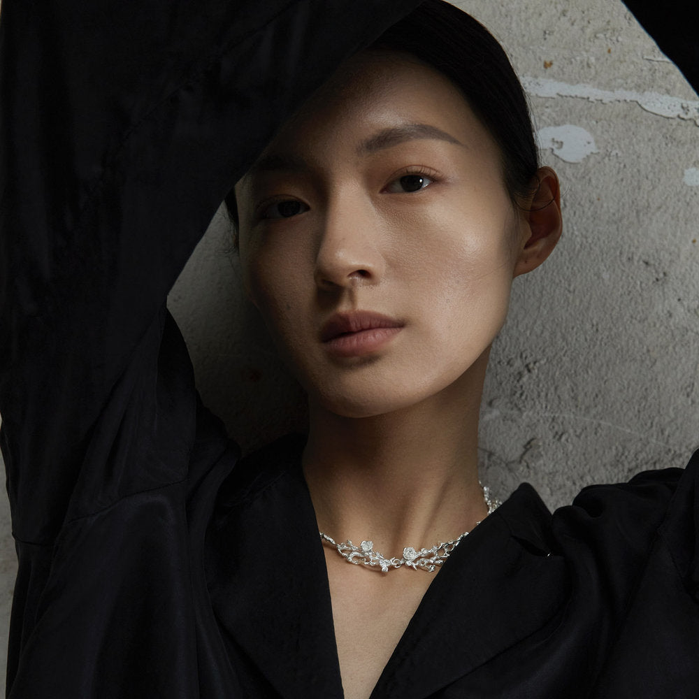 Person wearing a handcrafted silver rose branch choker