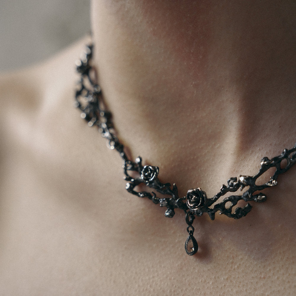 Black handcrafted botanical flower choker necklace on a person's neck