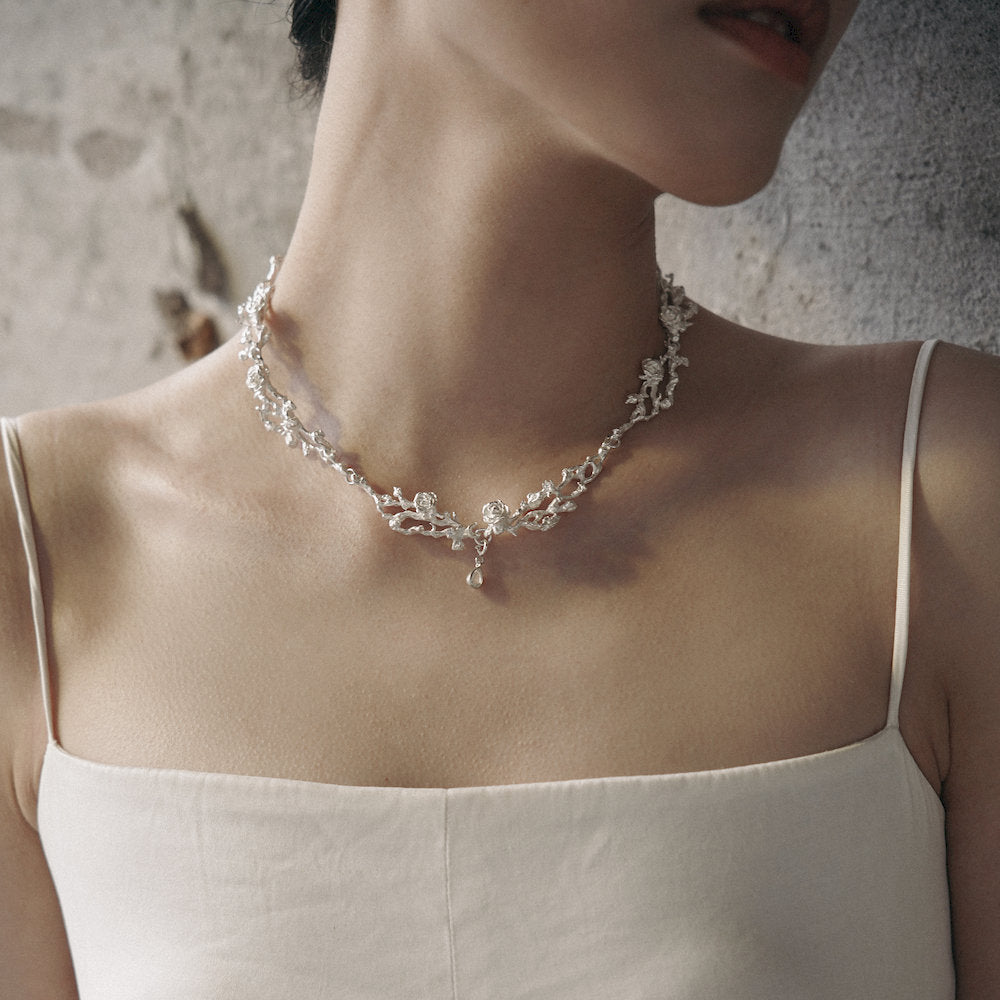 Woman wearing a delicate silver necklace with a white dress