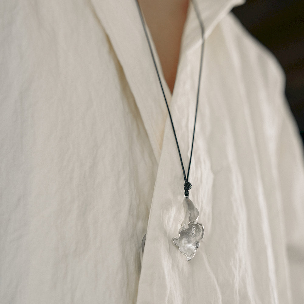 unisex Necklace with a polished silver calla pendant worn by a person